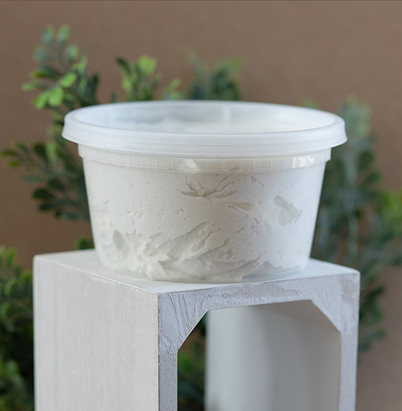 Tub of shea butter on a white pedestal.